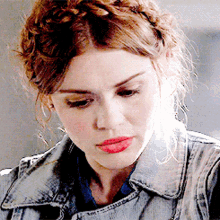 a close up of a woman wearing a denim jacket and a braided headband