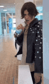 a man in a black leather jacket is drinking water from a bottle