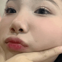 a close up of a person 's face with their hand on their chin