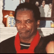 a man wearing a red scarf is standing in front of a mantle