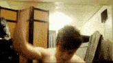 a shirtless man is standing in a room with a fan