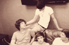 a group of young men are sitting on a couch and one of them is sitting on the couch .