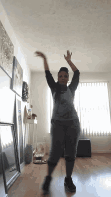 a woman is dancing in a room with her arms in the air