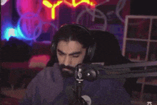 a man wearing headphones is sitting in front of a microphone and eating a snack .