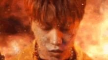 a close up of a person 's face with a fire background .