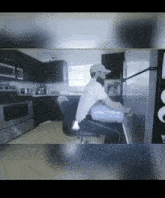 a man is sitting in a chair in a kitchen with a bag on his back .
