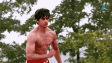 a shirtless man is running in front of trees with a zee tv logo