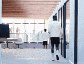 a man in a white shirt and black shorts walks in a hallway