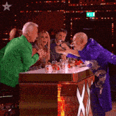 a group of people sitting at a table with a green star on the top