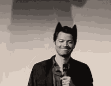 a man with cat ears on his head is holding a microphone and smiling .
