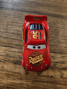 a red rusteze toy car is sitting on a wooden surface