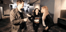 a man and two women are standing in a hallway and one of the women is wearing a virginia sweatshirt