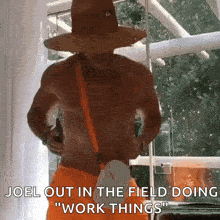 a shirtless man in a straw hat and orange shorts says joel out in the field doing work things