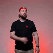 a man with a beard wearing a black shirt and a red hat is making a funny face .
