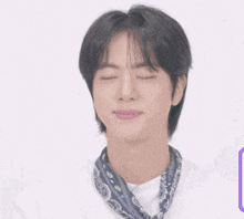 a close up of a person wearing a bandana and a white shirt with their eyes closed .