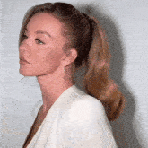 a woman wearing a ponytail and earrings looks to the side