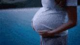 a pregnant woman is holding her belly in front of a blue background .