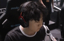 a person wearing headphones and a microphone is sitting in a chair with the word anda on the back .