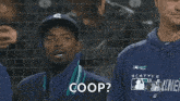 a man wearing a seattle mariners sweatshirt stands in front of a net .