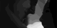 a black and white photo of a man and woman kissing each other .