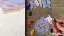 a painting is being painted on a wooden table with the words made in animatica on the bottom right
