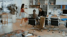 a woman is walking towards a man sitting at a desk in an office with the word abone on the bottom