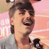 a man with a mustache holds a microphone in front of a sign that says glam on it