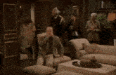 a man is sitting in a chair in a living room while a group of people are standing around him .