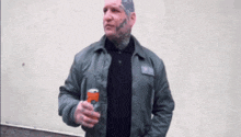 a man with a tattoo on his head is holding a can of soda and a bottle of soda .