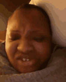 a close up of a person making a funny face while laying in bed .