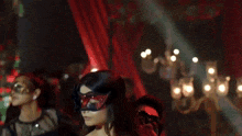 a woman in a red dress is dancing with a man in a black suit and mask .