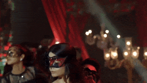 a woman in a red dress is dancing with a man in a black suit and mask .