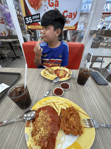 a boy is sitting at a table with a plate of food and a sign that says ga cay
