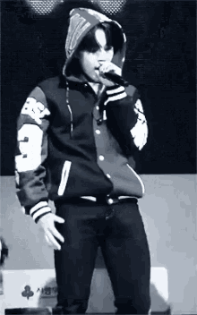 a man in a hoodie is singing into a microphone while standing on a stage .