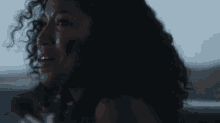 a woman with curly hair is sitting in the back seat of a car and crying .