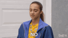 a girl wearing a blue jacket and a yellow shirt is saying no