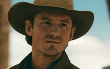 a man with a beard wearing a cowboy hat looks at the camera