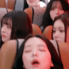 a group of girls are sitting on a bus with their eyes closed .