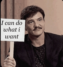 a man in a suit holds up a sign that says i can do what i want