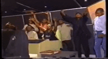 a group of people standing in a room with their arms in the air .
