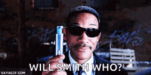 a man wearing sunglasses and a suit is holding a lighter and says will smith who