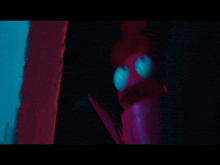 a purple toy with blue eyes is standing in a dark room