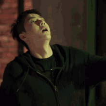 a man in a black hoodie is looking up at something