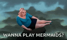 a woman is laying on a rock with the words `` wanna play mermaids ? '' written below her .