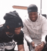 two men are sitting next to each other and one of them is wearing a shirt that says gt24h on it