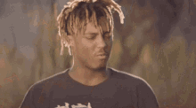 a man with dreadlocks is wearing a black t-shirt with chinese writing on it .
