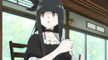 a girl with long black hair is sitting in a chair holding a red straw