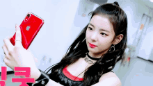a young woman is taking a selfie with her red iphone