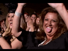 a woman sticking her tongue out while a group of women applaud