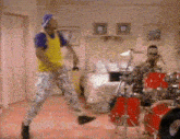 a man in a yellow shirt is dancing in front of a drum set .